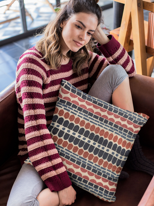 Red and blue striped brick throw pillow held on a couch cushion.