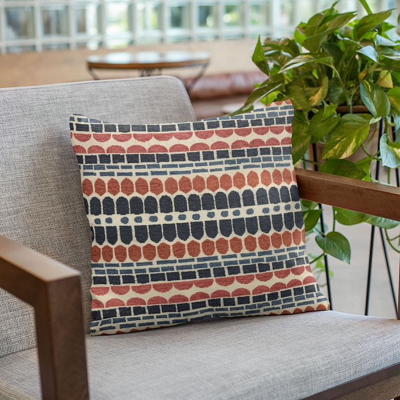Red and blue brick-pattern throw pillow on a fabric chair arm.