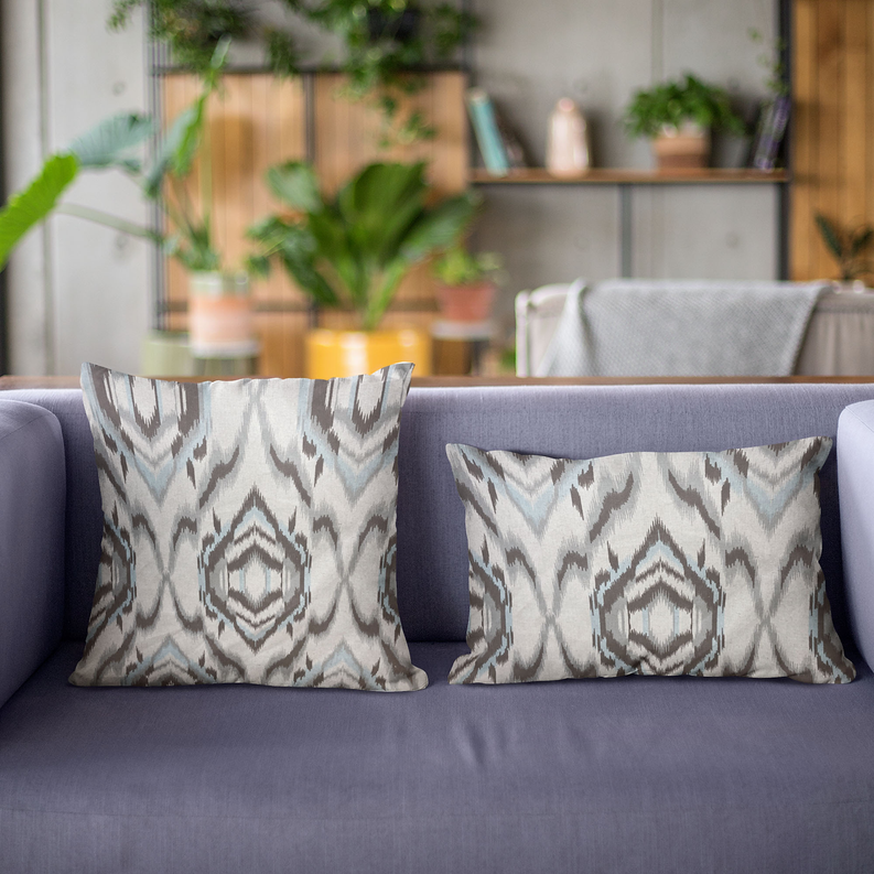 Pair of ikat throw pillows on a sofa, cream and light blue with dark gray patterns