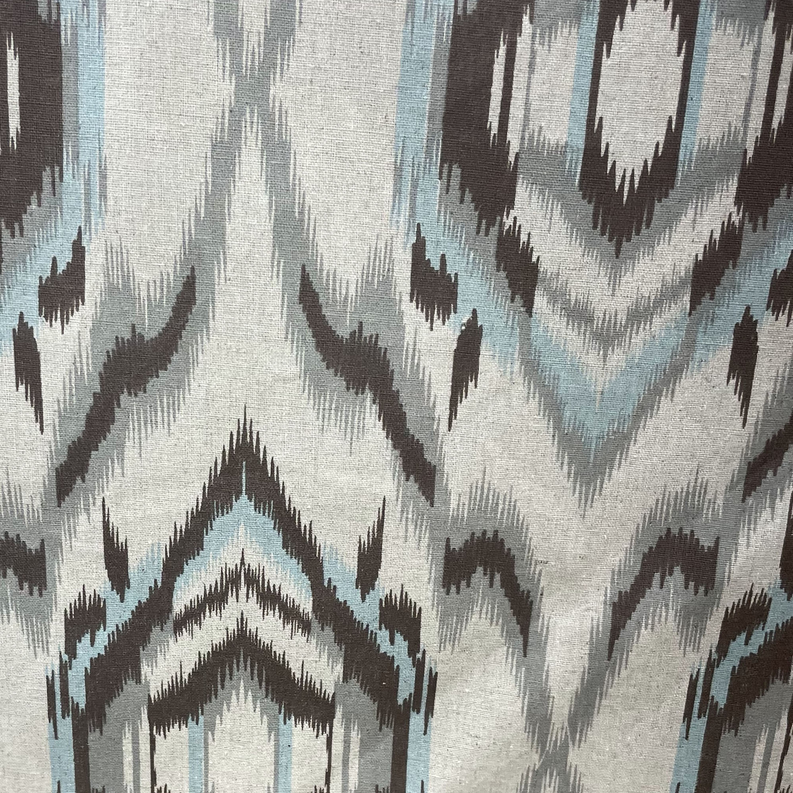 Ikat pillow fabric close-up with blue and black geometric motifs on cream weave