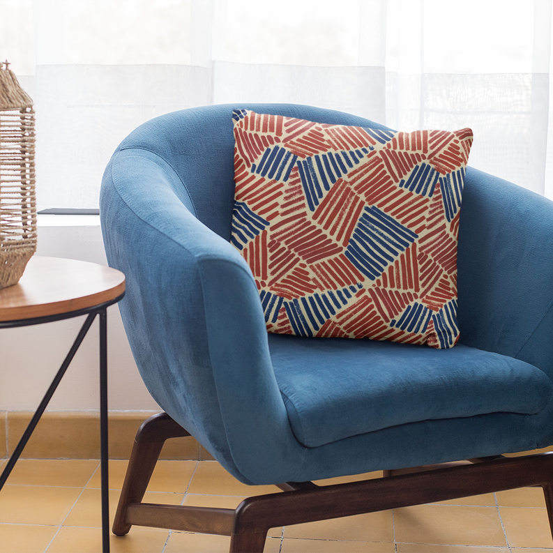 Red and blue abstract sketch throw pillow on a blue upholstered chair