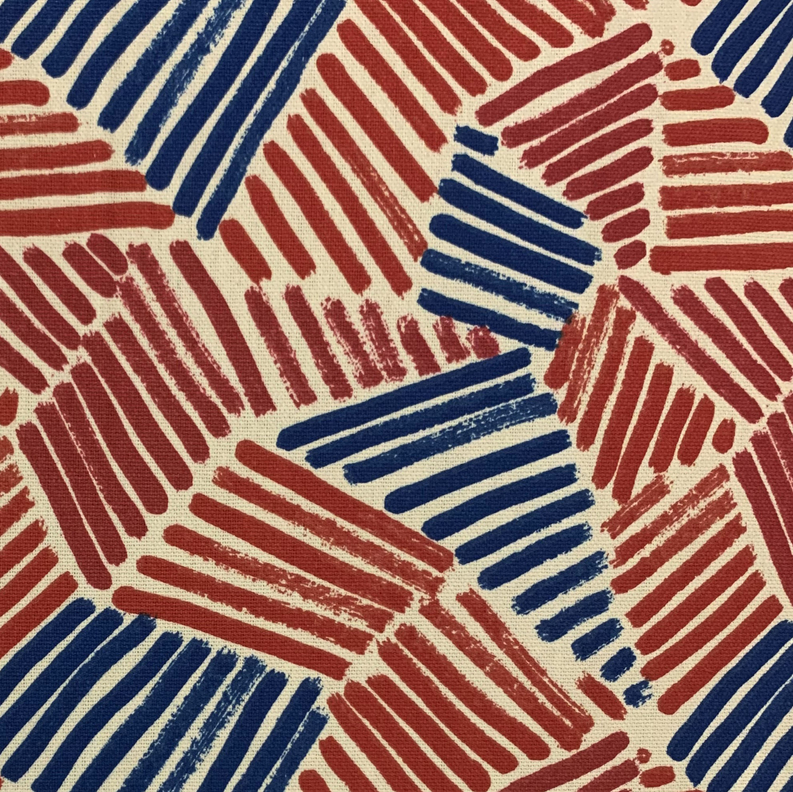 Luxury throw pillow fabric close-up with rust red and navy blue geometric lines on cream