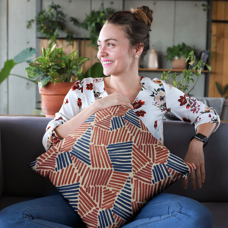 Luxury throw pillow with red and blue abstract sketch pattern held against a white top