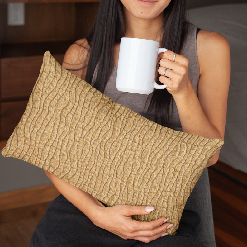 Yellow textured throw pillow with wavy desert-line pattern, held in hands