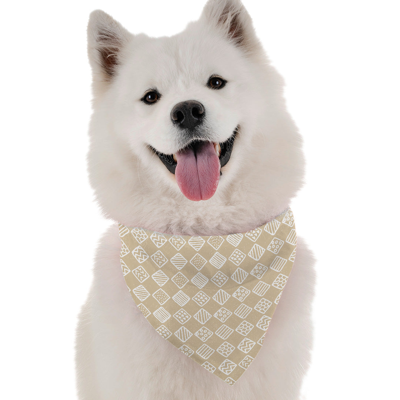 White dog wearing tan and white patterned bandana with overhand tie