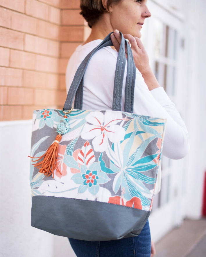 Floral canvas tote bag with gray handles, tassel keychain, and wide gray base