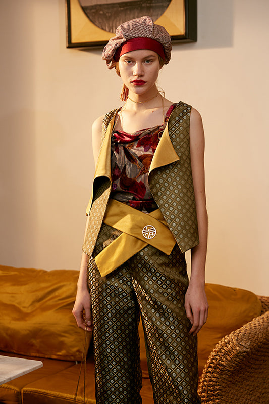 Yellow corset belt with layered panels and gold logo at front over patterned trousers