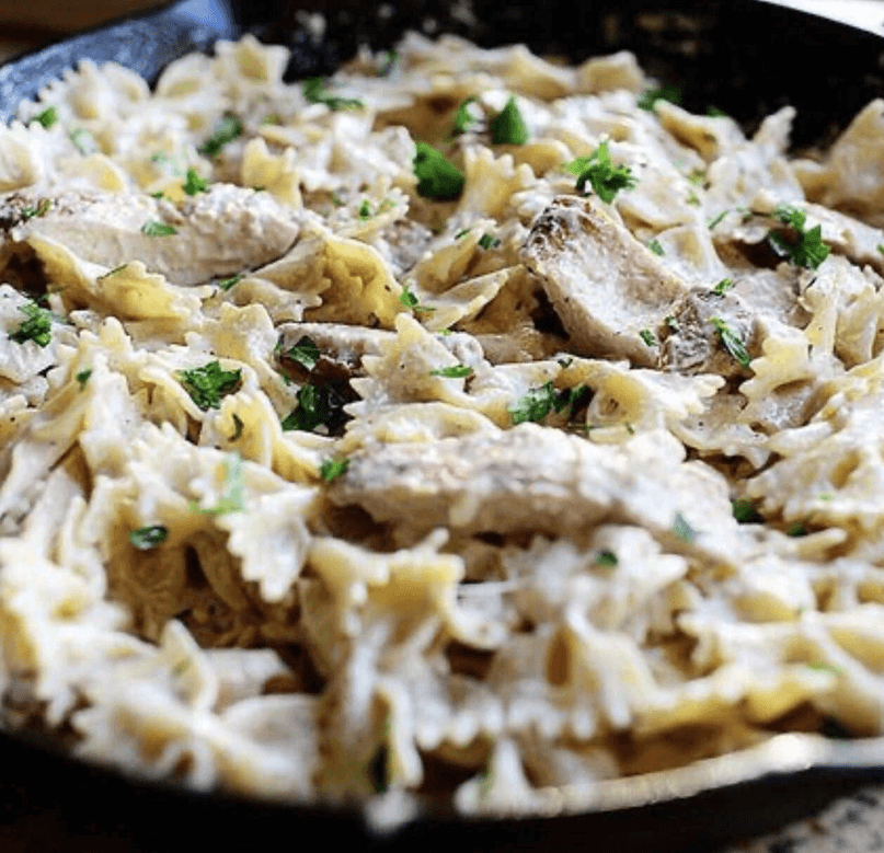 Creamy chicken alfredo pasta with chicken pieces and chopped herbs