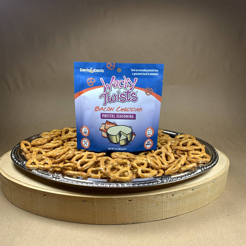 Blue bacon cheddar pretzel seasoning pouch behind a platter of pretzel twists