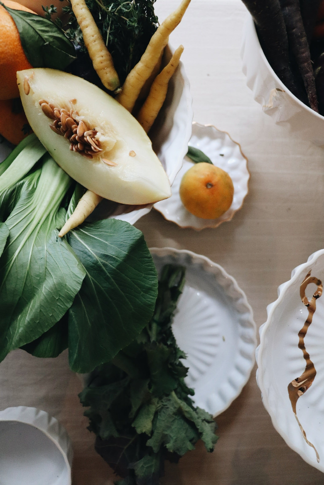 Handmade ceramic dinner plate with white ridged rim and embossed center, styled with vegetables