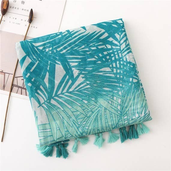 Turquoise leaf-pattern scarf with teal tassel fringe along the bottom edge