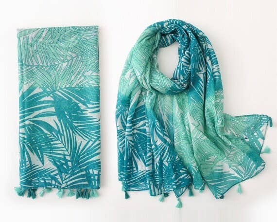 Turquoise leaf-pattern scarf with matching teal tassel fringe, folded and draped view
