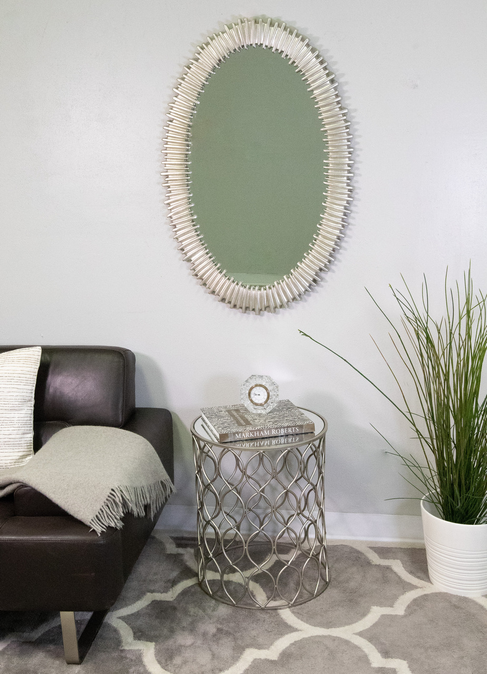 Oval wall mirror with silver ribbed frame and reflective glass panel.