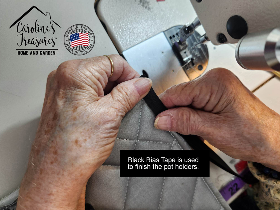 Quilted pot holder being finished by hand, showing gray fabric with black binding