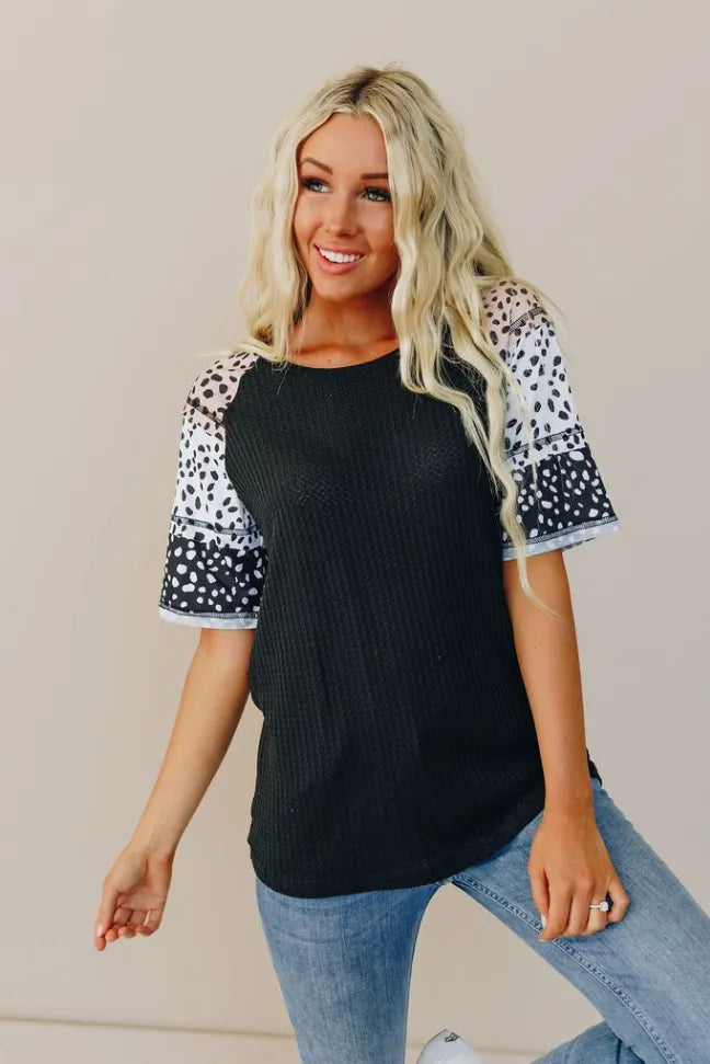 Black short-sleeve top with white dot-print sleeves, crew neckline; front view