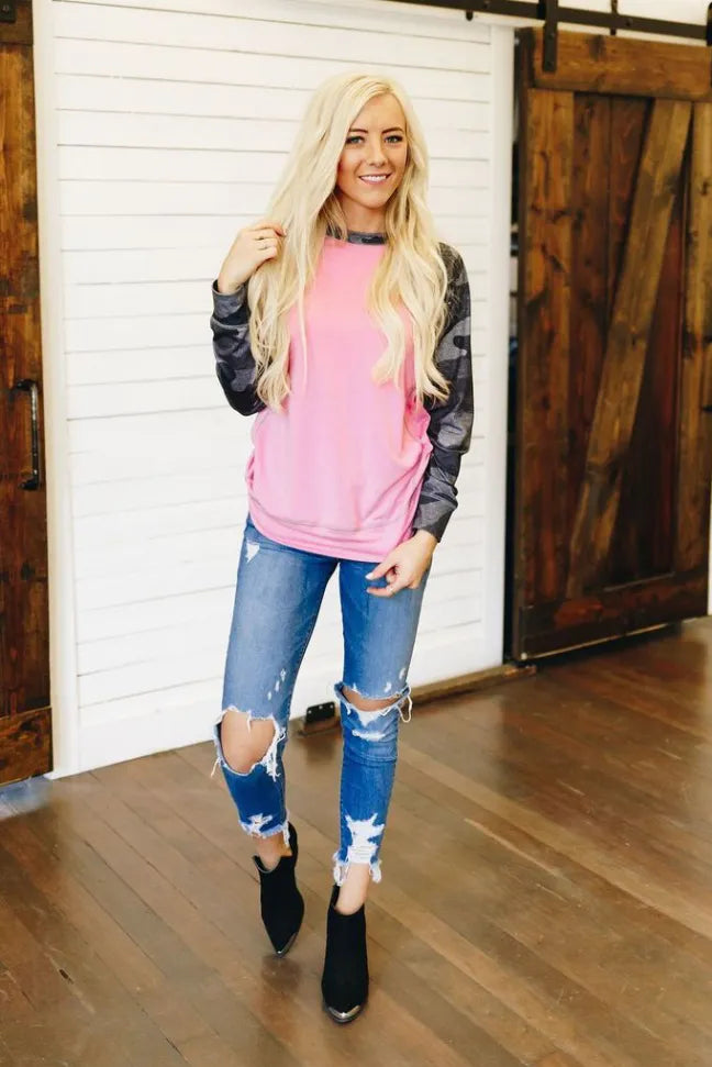 Pink crewneck pullover with dark camo sleeves and ribbed cuffs, front view