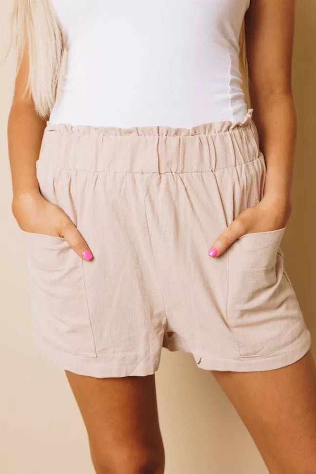 Light beige shorts with elastic waistband, side pockets, above-knee relaxed fit