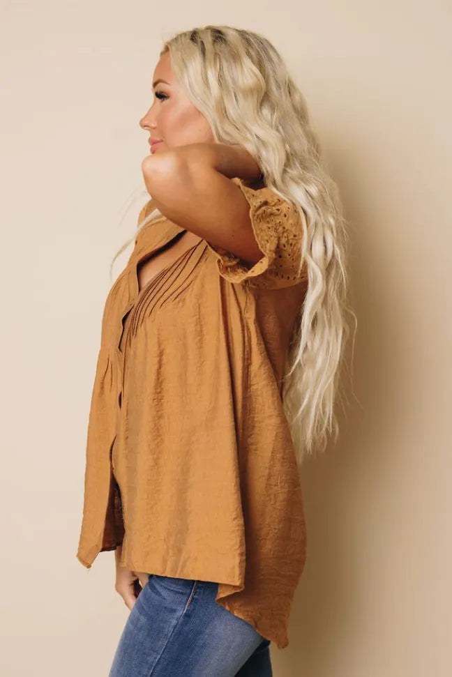 Camel brown pleated blouse with V-neck buttons and textured eyelet sleeves; side view