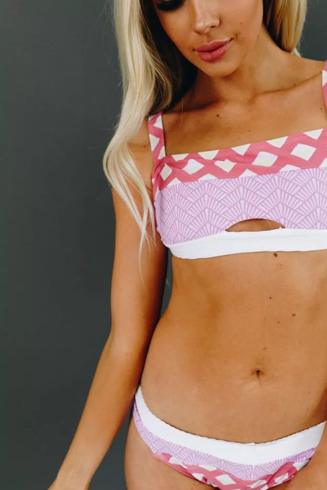 Pink patterned bikini top with white trim and matching bottoms, cropped close-up