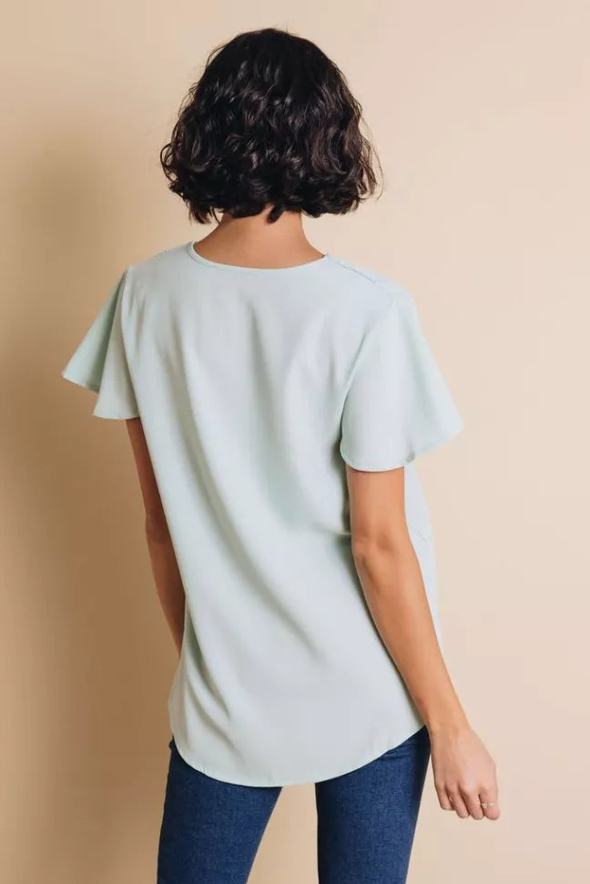 Light blue short-sleeve V-neck blouse on model, back view