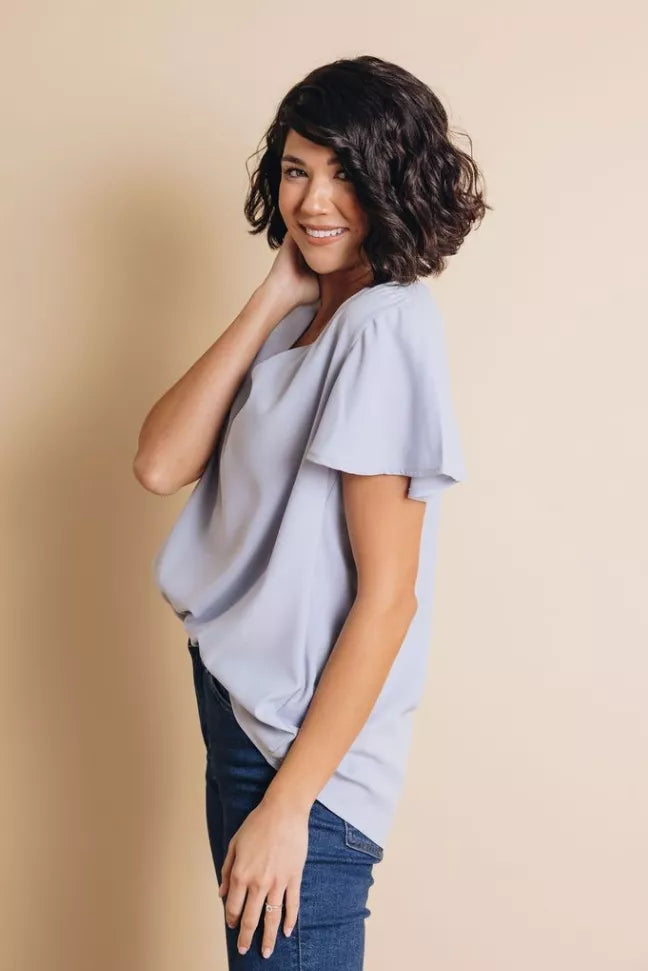 Light blue V-neck short-sleeve top with draped sides and relaxed shoulder fit