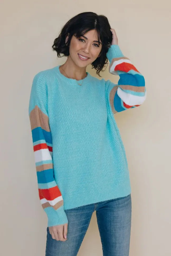 Light blue crewneck striped sweater with multicolor striped sleeves and ribbed cuffs, front view