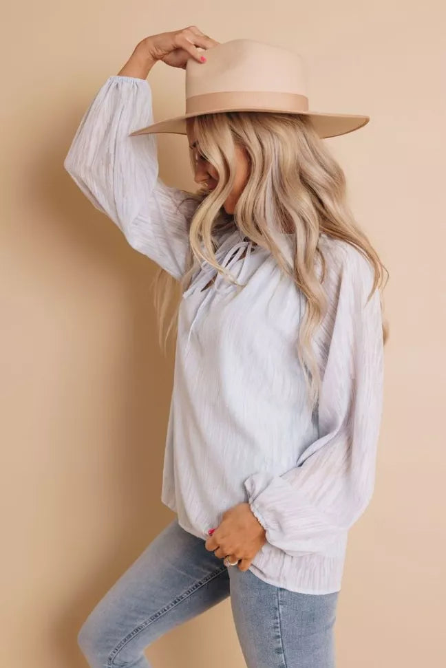 Light blue peasant blouse with keyhole neckline and long puff sleeves, side profile