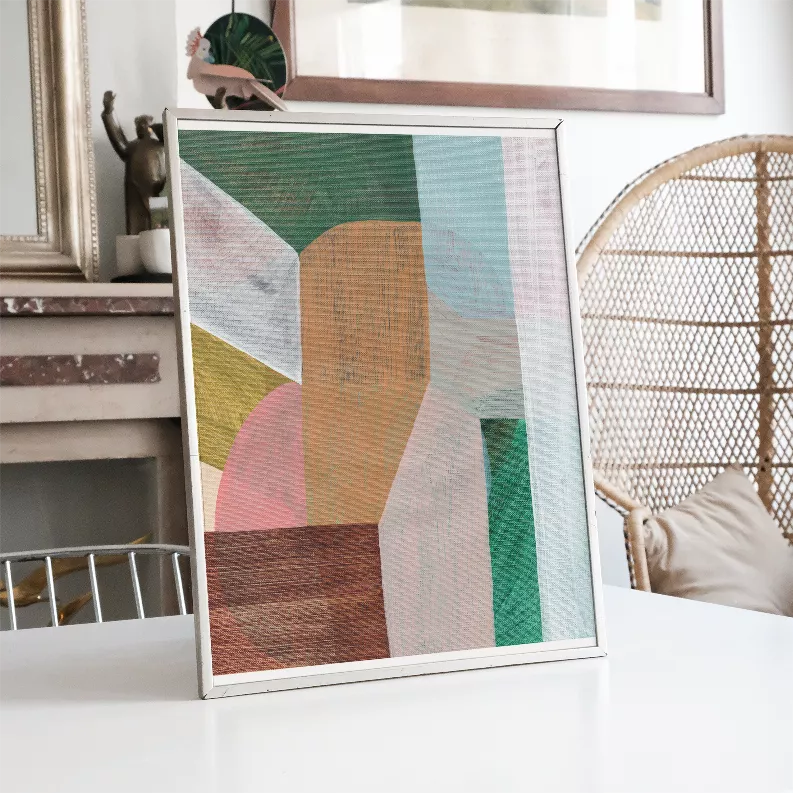 Framed abstract wall art print on furniture, geometric green and orange panels with pink accents