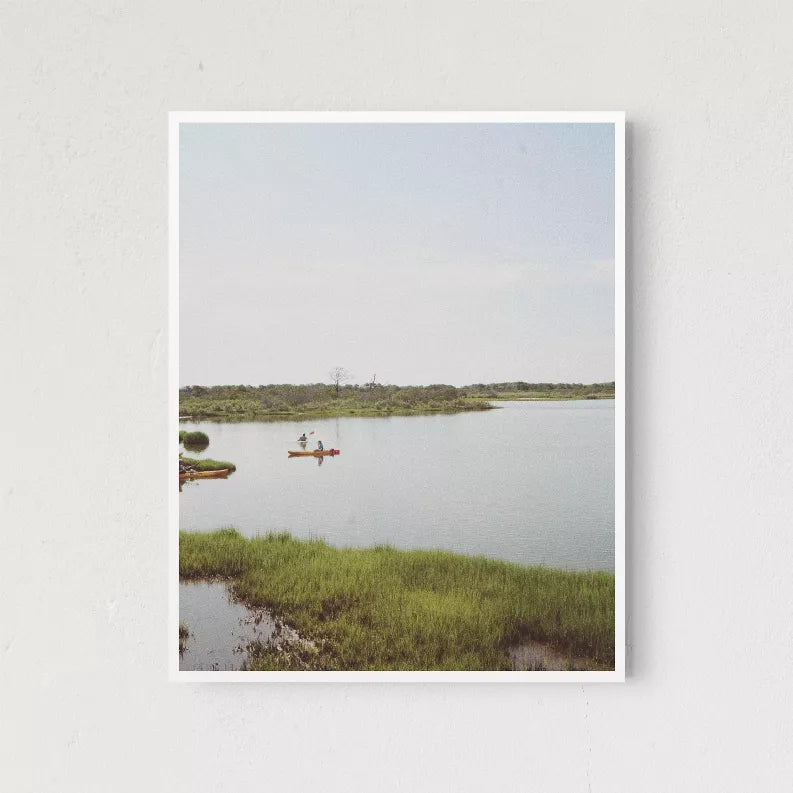 Framed lake landscape photo print with small boats on calm water and grassy shore