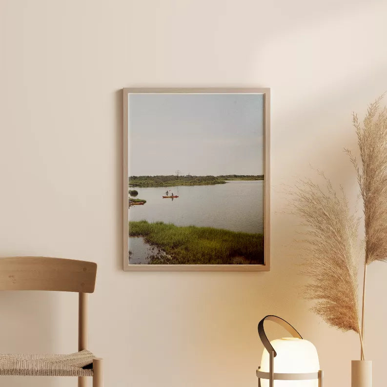 Rectangular framed landscape photo with calm lake, small boats, and grassy shoreline