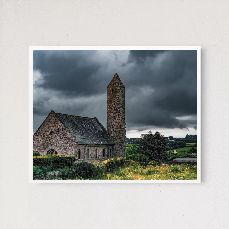Wooden-framed landscape photo print featuring stone church tower under storm clouds