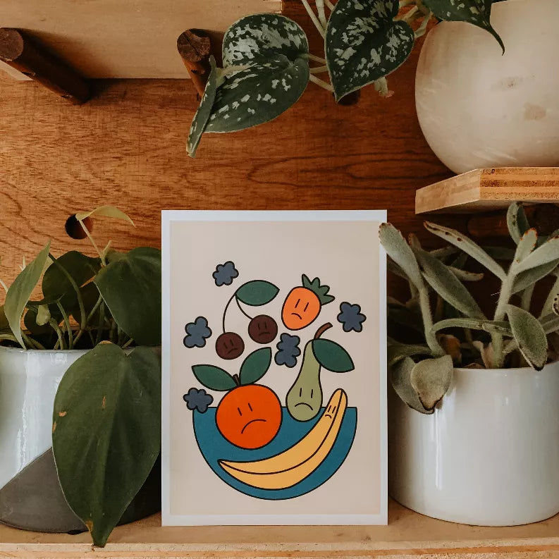 Colorful fruit and leaves illustration card in a white frame, featuring a smiling banana.