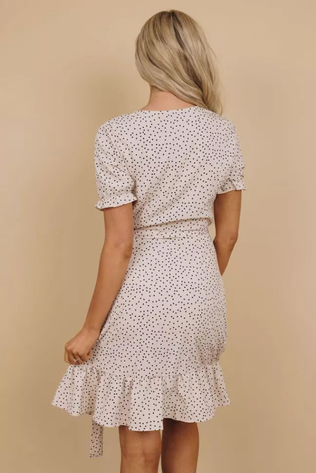 White dotted wrap dress back view with short sleeves and tie waist, tiered ruffle hem