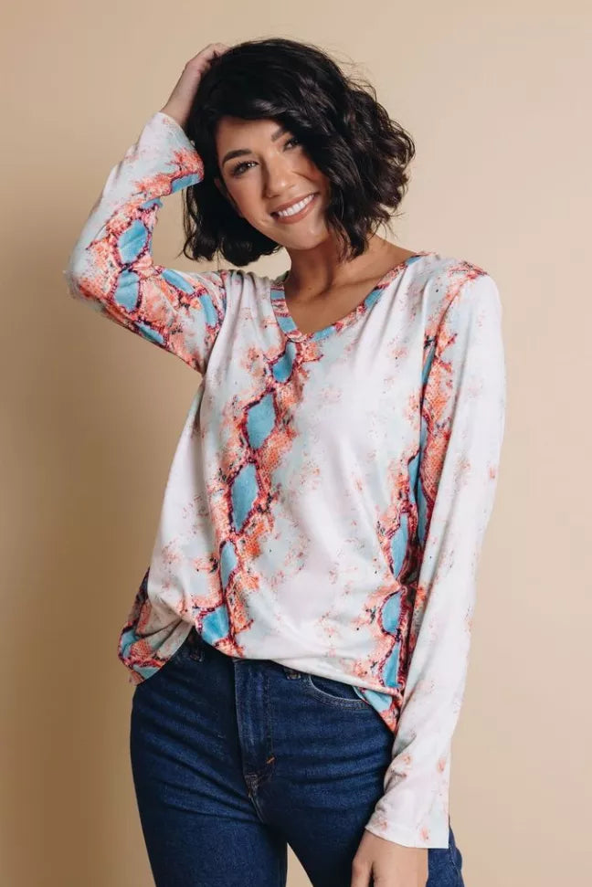 Snakeskin print V-neck long-sleeve top, white with coral and blue pattern, smiling pose