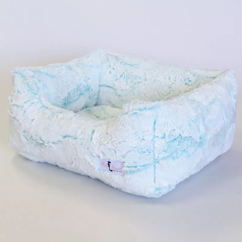 Blue-and-white plush dog bed with cushioned walls and raised center bolster, low rectangular