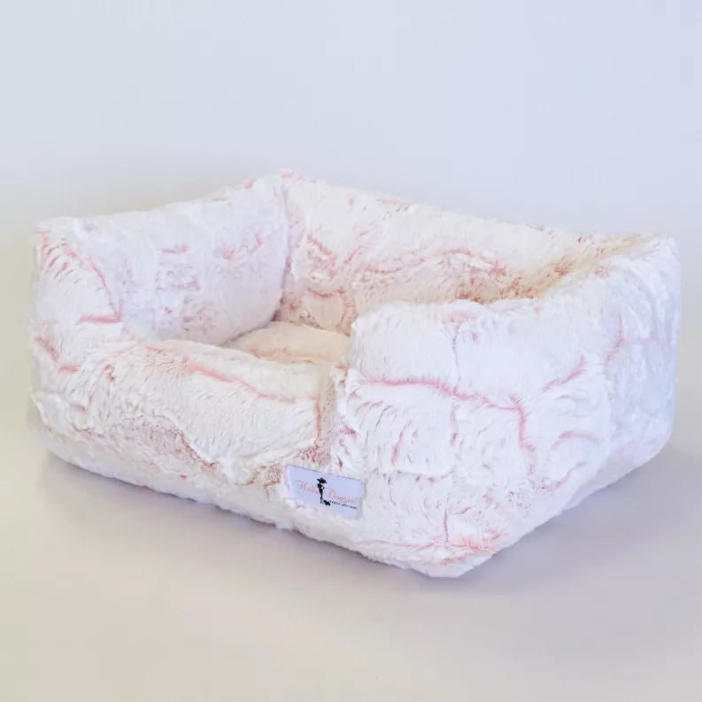 Plush dog bed in white with pink pattern, cushioned sides and front fabric tag.