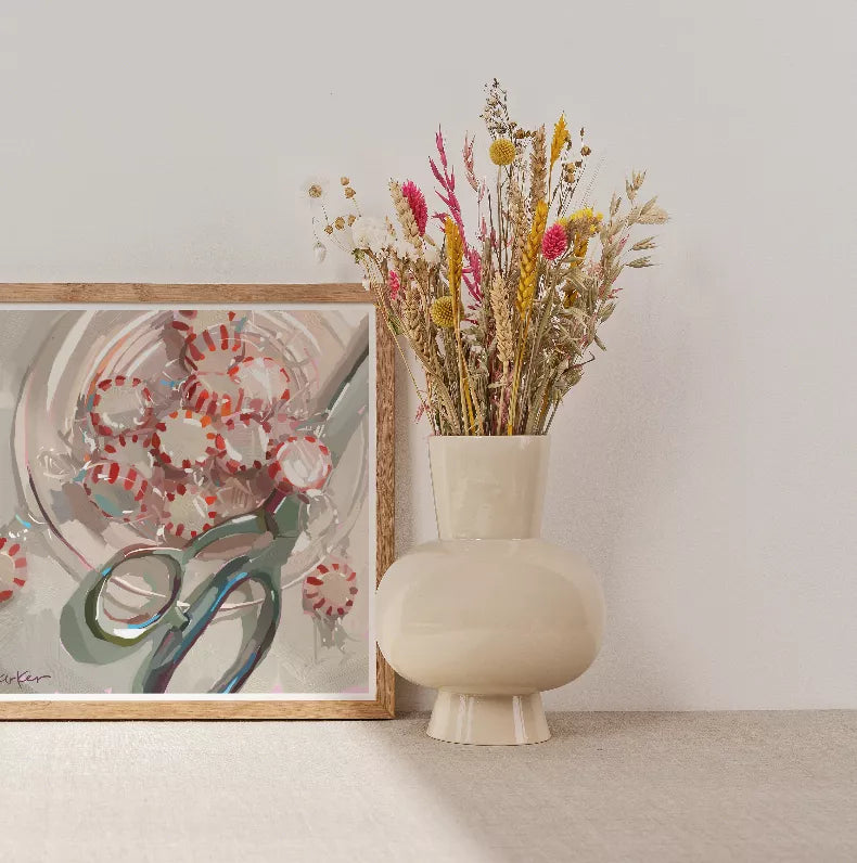 Dried flower bouquet in cream vase with partial framed abstract artwork