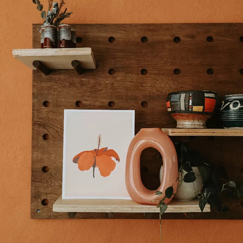 Hibiscus flower framed print with orange petals and a yellow-tipped stem on pale background