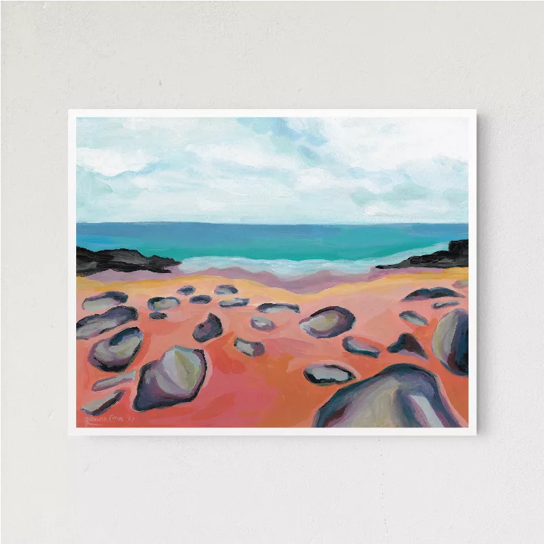 Framed beach landscape print showing rocks in orange sand and teal waves