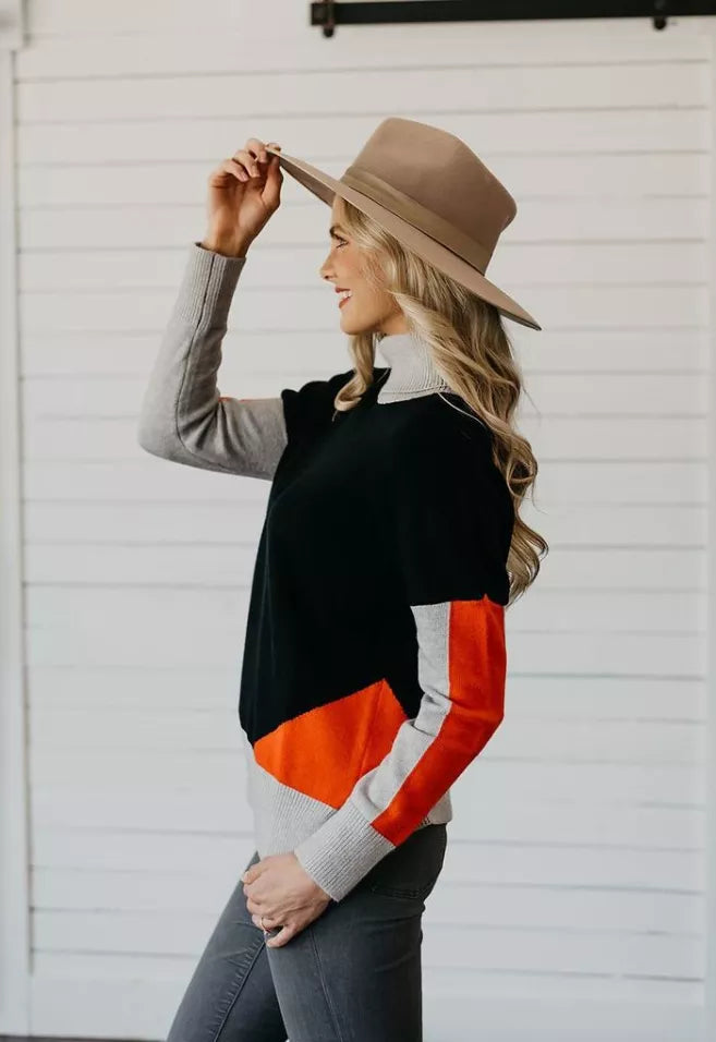 Women's color-block turtleneck sweater in black with orange and white side panel, side view