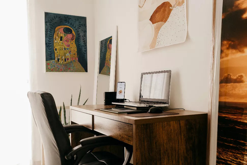 Framed painting print on a wall, featuring a woman in gold and teal under leaves.