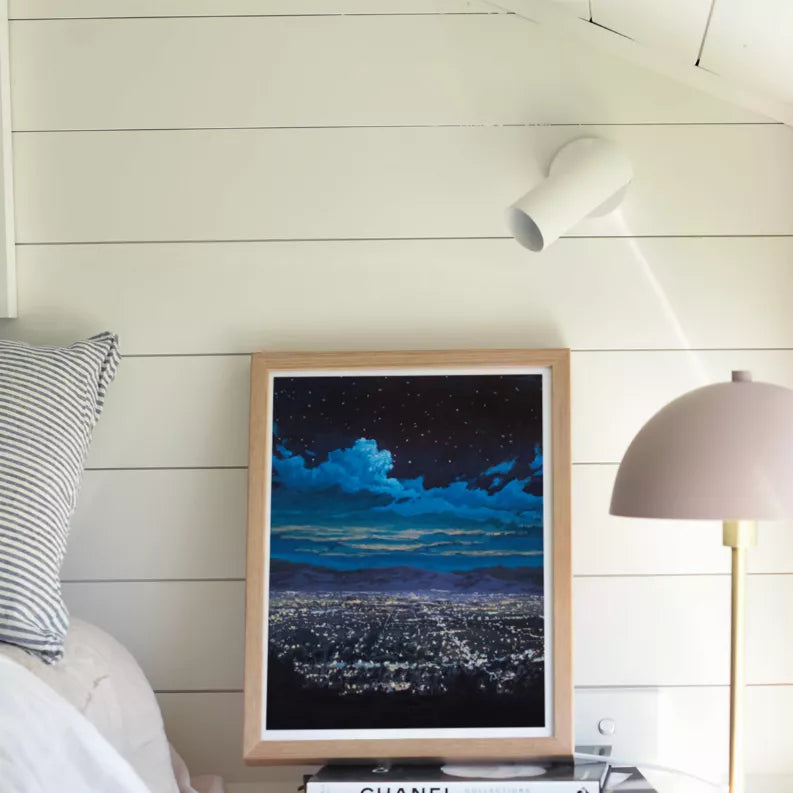 Framed night cityscape wall art print with wood frame and white border, blue clouds sky