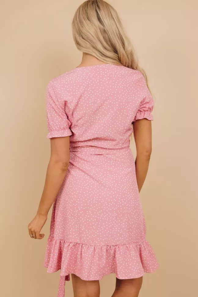 Back view of pink dotted wrap dress with puff sleeves and tiered ruffle hem