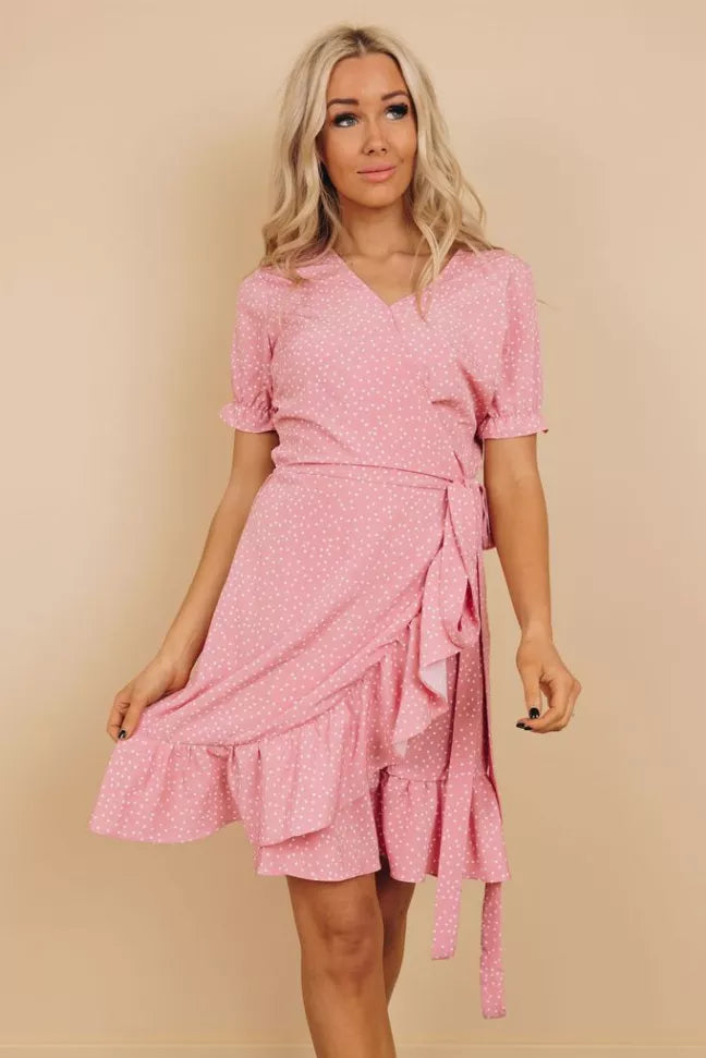 Pink dotted wrap dress with short puff sleeves, V-neck, and tiered ruffle skirt hem