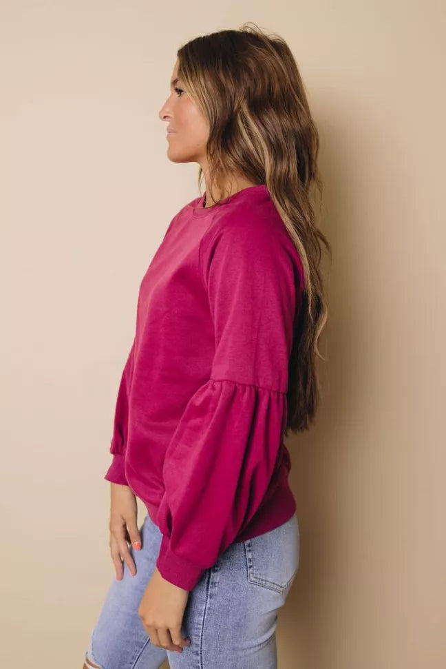Magenta balloon-sleeve crewneck sweatshirt, side view with gathered cuffs