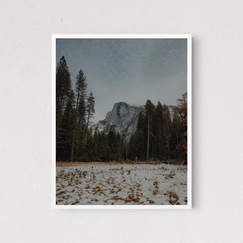 Framed landscape print with snowy pines and Half Dome-style granite peak, white border