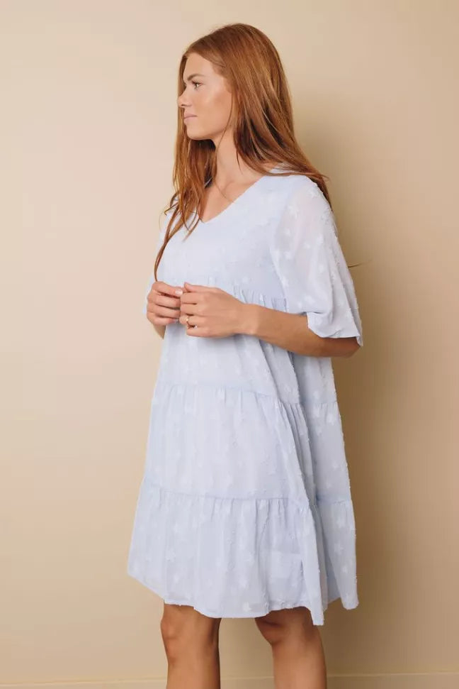 Light blue babydoll dress with V-neck and tiered layers, front side view