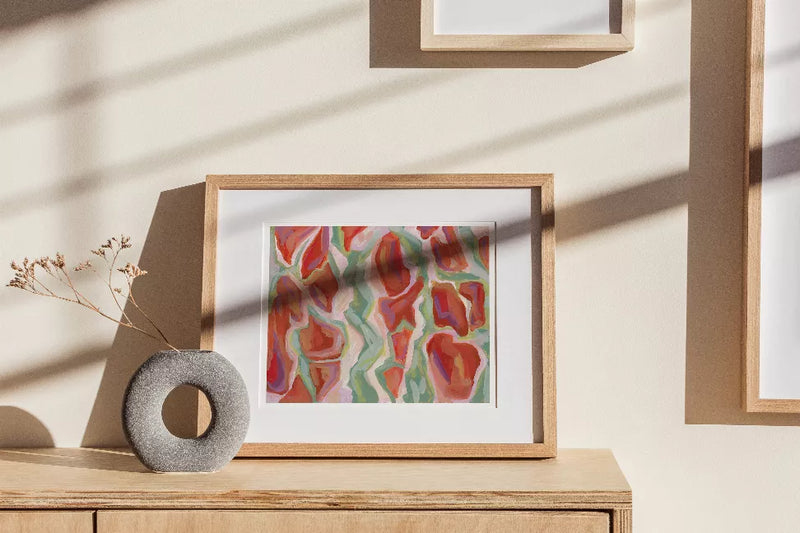 Framed abstract tree bark print in pastel teal, coral, and orange on a stand