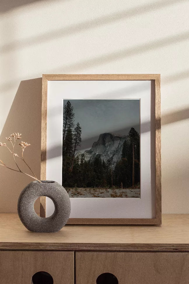 Half Dome landscape print in a light wood frame, snowy pines and mountain peak