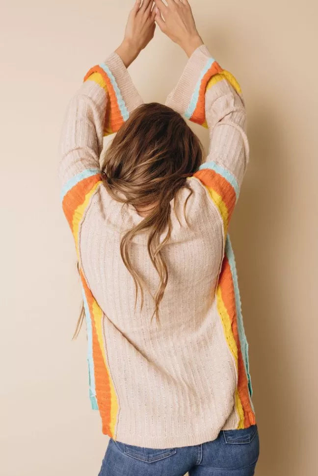 Back of cream knit sweater with rainbow striped bell sleeves and crew neckline